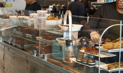 Staff Working Behind Counter In Busy Coffee Shop